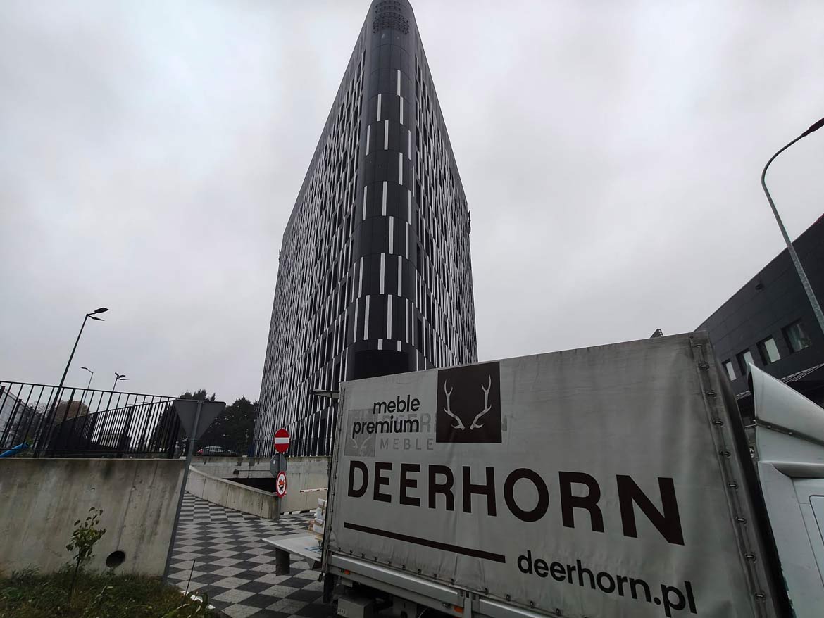 Auto mit großem Deerhorn-Logo, im Hintergrund der moderne DL Tower-Wolkenkratzer in Kattowitz, Polen