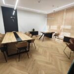 Modernes Büro mit großem Konferenztisch und Schreibtisch am Fenster