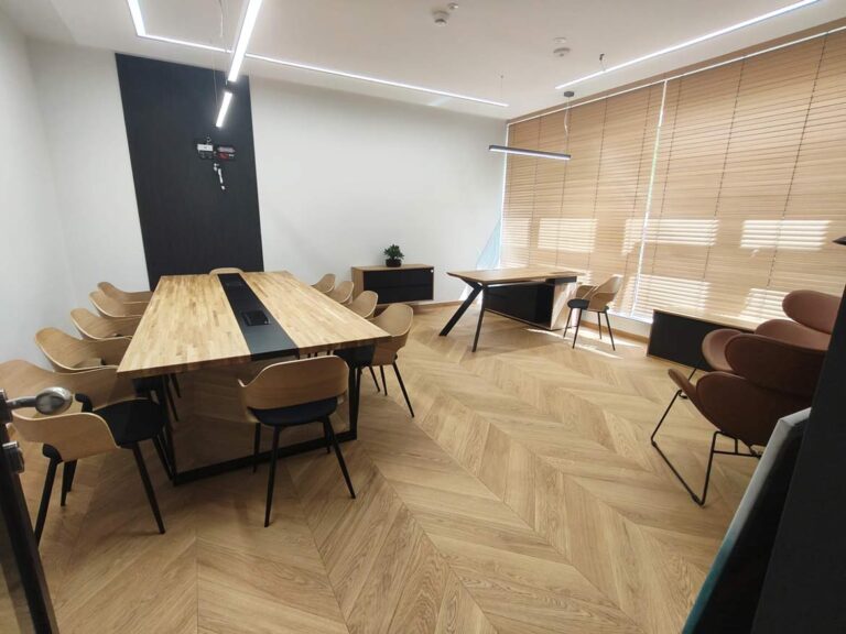 Modernes Büro mit großem Konferenztisch und Schreibtisch am Fenster