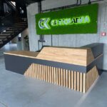 Moderner Empfangstresen mit Holzplatte und geometrischer Front in einem industriellen Interieur