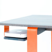 Schreibtisch mit orangefarbenem Gestell und Platz für einen Mac mini